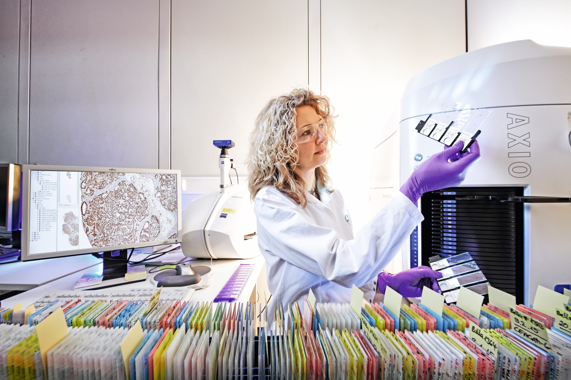 Una mujer con bata de laboratorio observa atentamente a través de un microscopio en un entorno científico