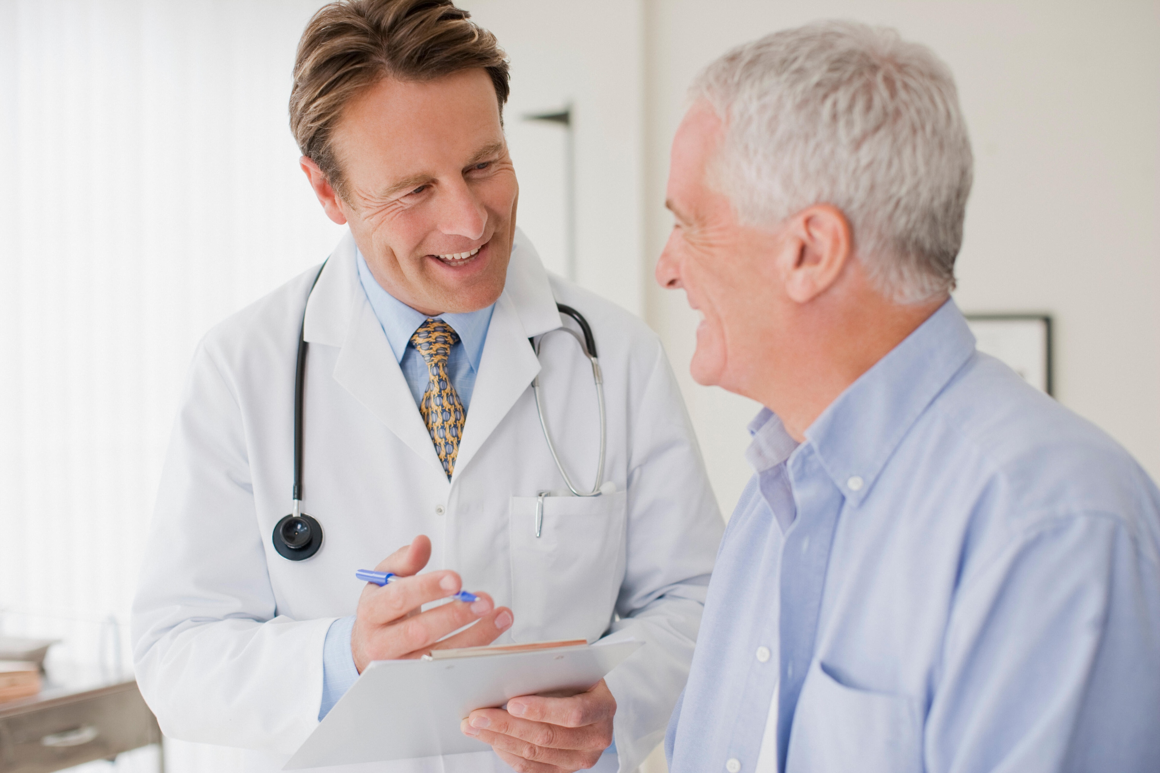 Un médico conversando con un paciente en un entorno clínico, mostrando atención y profesionalismo.