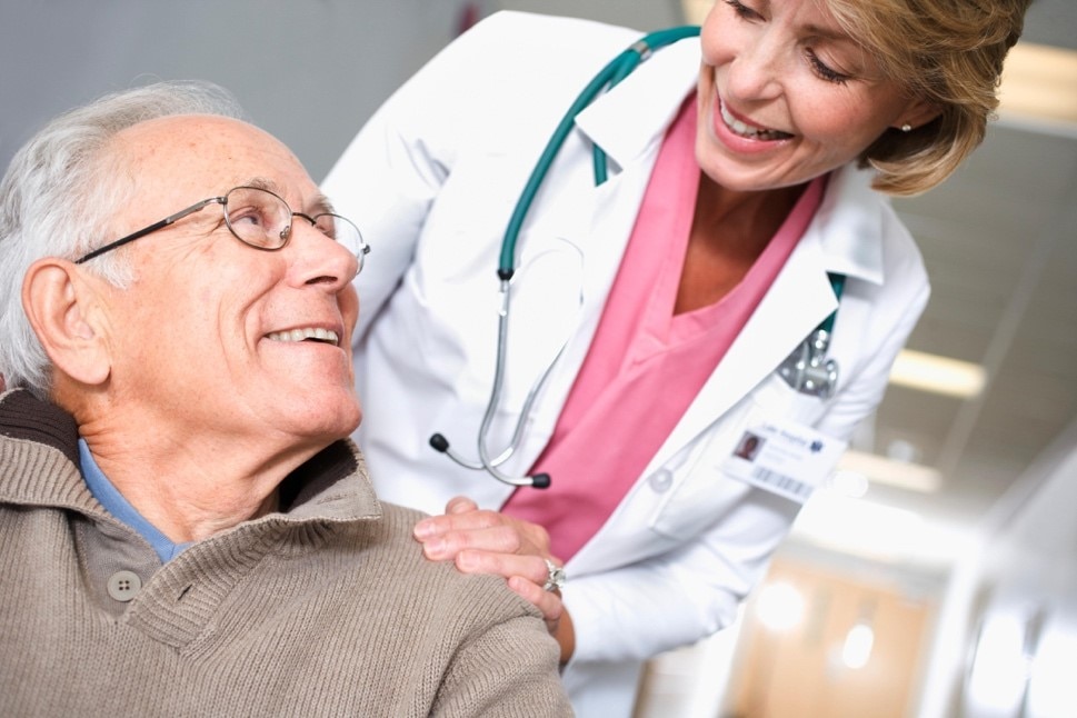 Un médico y un hombre de edad avanzada intercambiando palabras, destacando la importancia de la comunicación en la salud.